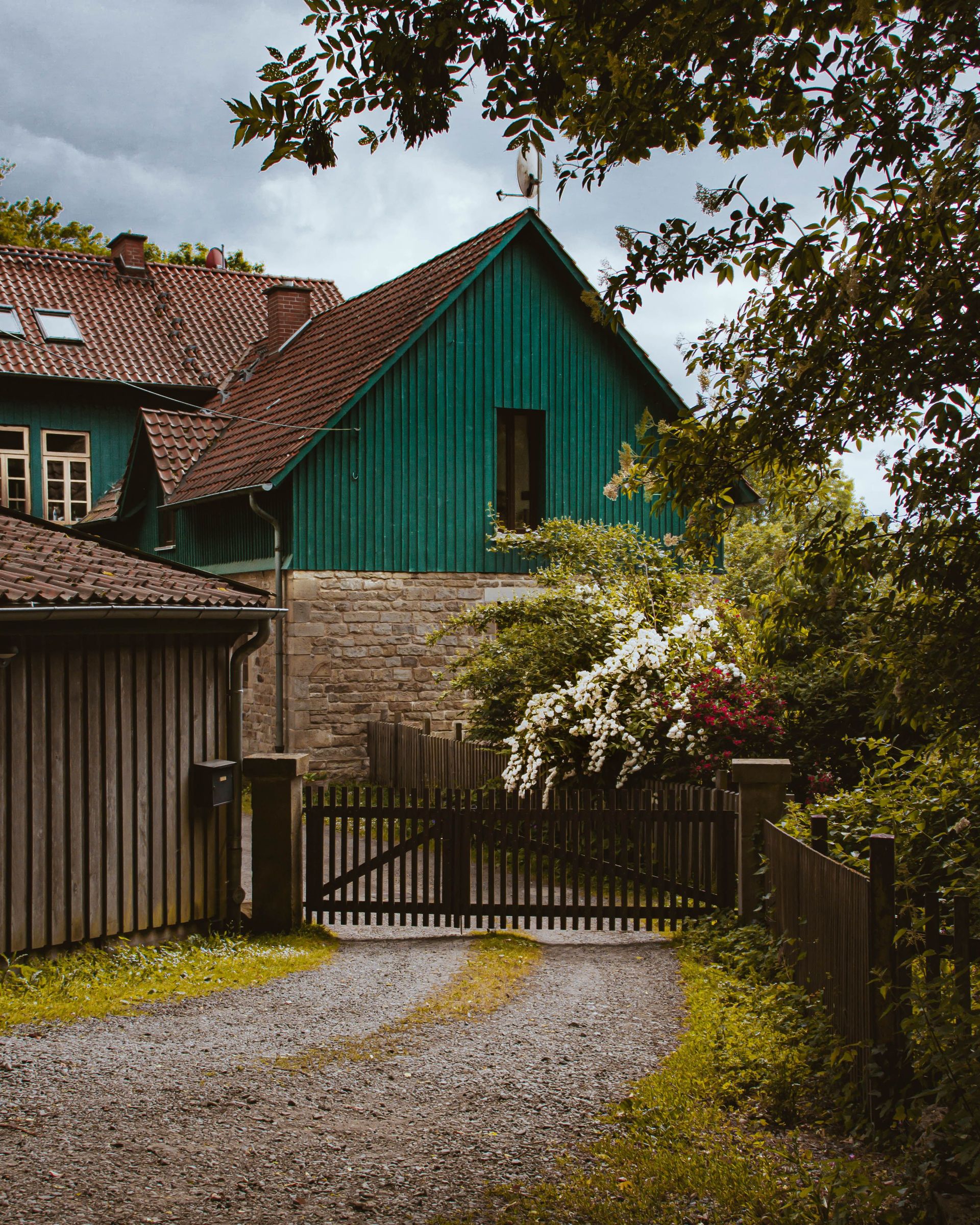 Picturesque rural house with vibrant garden and wooden gate.